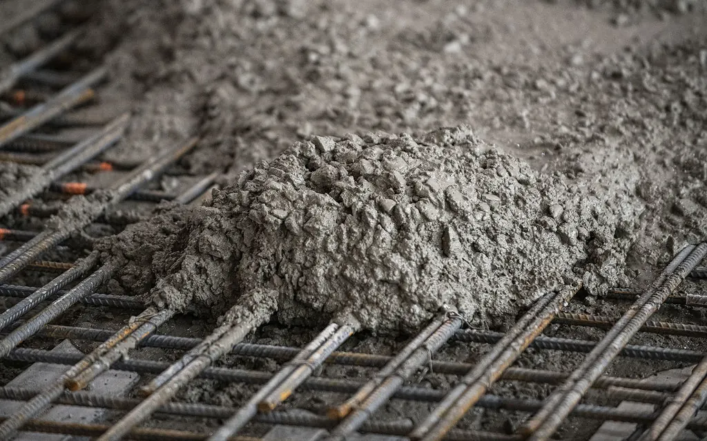 Fresh concrete being poured over reinforcing steel during a slab replacement